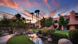 Ein Resort mit Pool, Palmen und einem Sonnenuntergangshimmel.