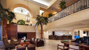 Eine geräumige Lobby mit hoher Decke, einem Empfangsschalter, bequemen Sitzgelegenheiten und einem großen Fernsehbildschirm.