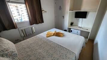 Una habitación de hotel con una cama, un escritorio, un televisor y una ventana con cortinas.