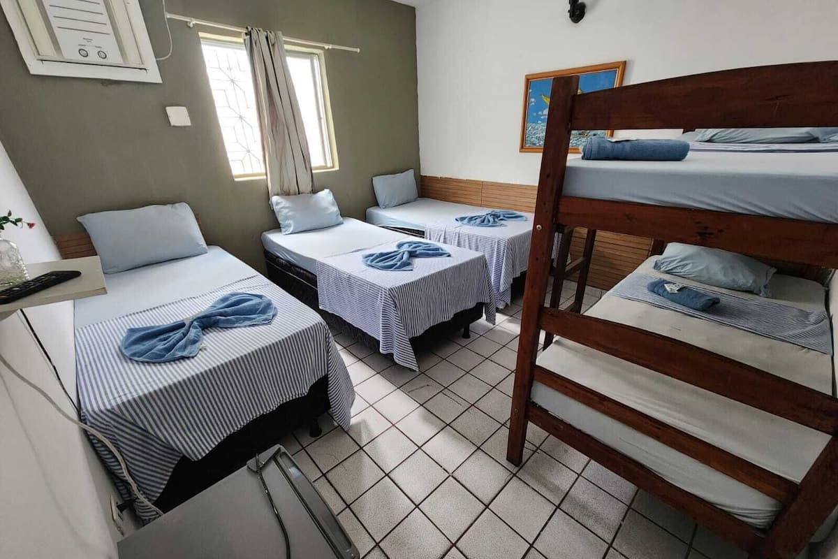 Un dormitorio con literas, dos camas individuales, un escritorio y una ventana.