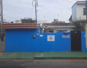 A blue gate with a house logo, a number '399', and a green area in front. - Casa do Meio Pousada (Recife)