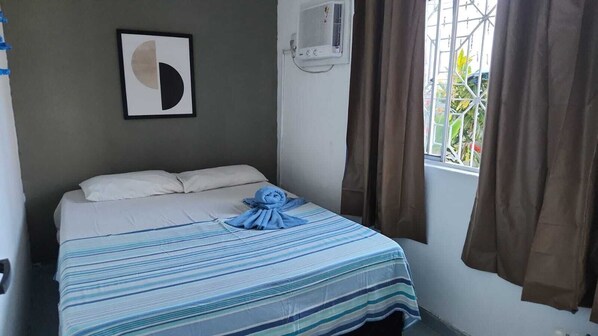 A hotel room with a bed, a framed artwork, an air conditioning unit, and a window with curtains. - Casa do Meio Pousada (Recife)