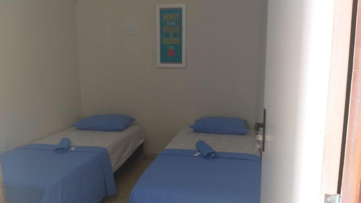 A room with two single beds, each with a blue bedspread and matching pillow.