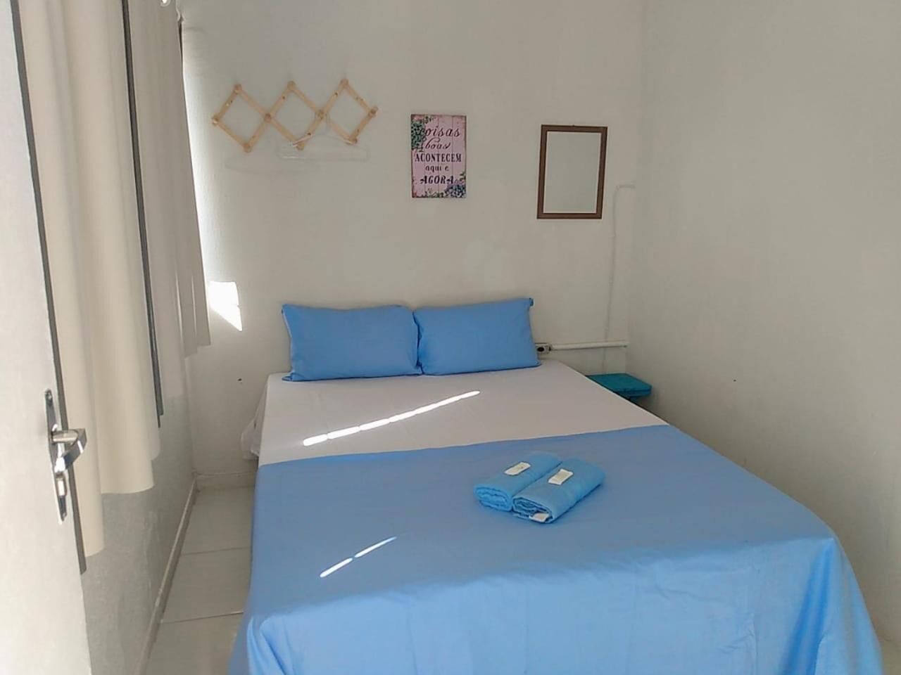 A small, clean room with a bed, a wall decoration, and a door.