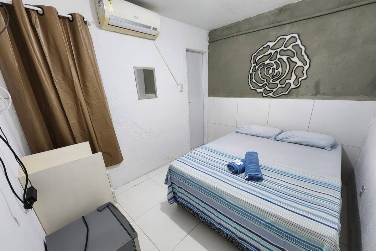 Un dormitorio con cama, aire acondicionado de pared, ventana y un adorno en la pared.
