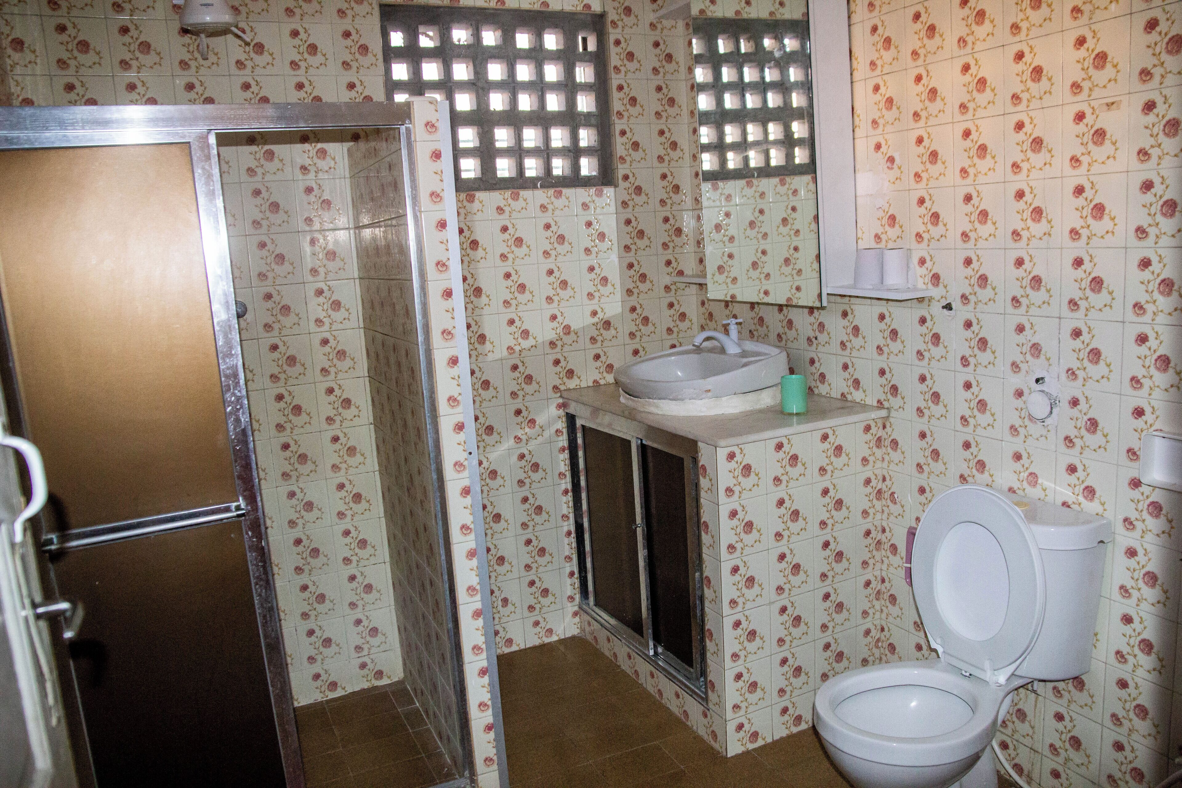 A bathroom with a shower, toilet, sink, and a mirror.
