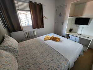 A hotel room with a bed, a desk with a computer, a TV, and a window with curtains. - Casa do Meio Pousada (Recife)