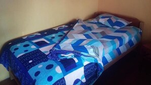 A single bed with a blue and white patterned bedspread and pillows. - Casa Refugio House (Cusco)