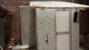 A small utility room with a tiled wall, a metal door, and a corrugated roof. - Casa Refugio House (Cusco)