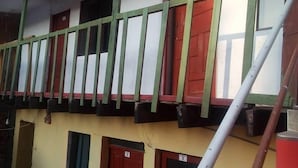A multi-story building with balconies, red doors, and a ladder. - Casa Refugio House (Cusco)