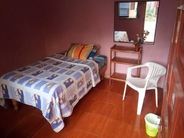A bedroom with a bed, a small table, a chair, and a window with a view of the outside. - Casa Refugio House (Cusco)