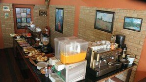 A buffet setup with various food items, a coffee machine, and a juice dispenser. - Pousada no Caminho do Marimbondo (Itatiaia)