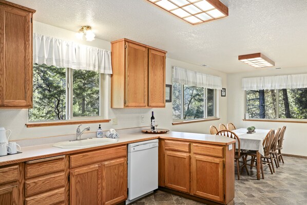 A kitchen with wooden cabinets, a dishwasher, and a dining area with a table and chairs.