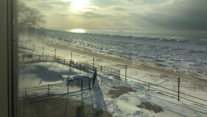 A snowy beach with a fence and a view of the ocean. - BEACHFRONT LAKE FACING Lake Michigan 1BR - private beach/heated pool/sundeck! (South Haven)
