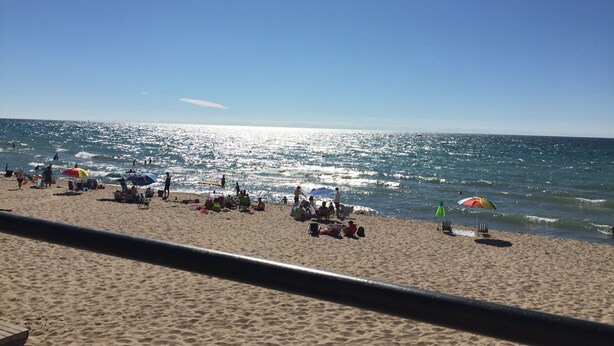 A beach with people, umbrellas, and beach chairs. - BEACHFRONT LAKE FACING Lake Michigan 1BR - private beach/heated pool/sundeck! (South Haven)