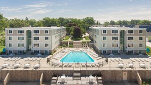 A hotel with a central swimming pool surrounded by sun loungers and a covered patio area. - BEACHFRONT LAKE FACING Lake Michigan 1BR - private beach/heated pool/sundeck! (South Haven)