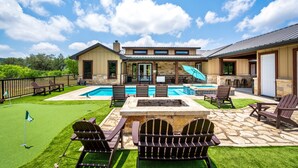 A backyard with a swimming pool, patio furniture, and a stone fireplace. - Private pool & hot tub, outdoor kitchen, putting green & more, 5-minute drive to THE Frio River (Concan)