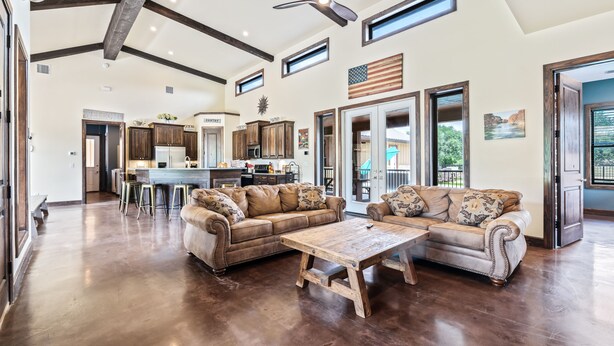 A spacious living room with a large wooden coffee table, two leather sofas, and a ceiling fan. - Private pool & hot tub, outdoor kitchen, putting green & more, 5-minute drive to THE Frio River (Concan)