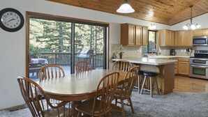 Une cuisine spacieuse dotée de meubles en bois, d’un grand îlot central et d’un coin repas avec des chaises en bois.