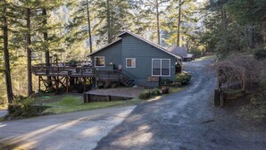 Une cabane dotée d’une terrasse, entourée de grands arbres.