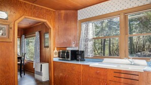 Une cuisine compacte avec des meubles en bois, un four à micro-ondes encastré et une machine à café.