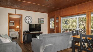 Un salon chaleureux avec un canapé gris, un téléviseur à écran plat et un plafond en bois.