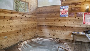 L’intérieur d’un chalet en bois, avec un jacuzzi, des murs en bois et un panneau indiquant : « AUCUN SAUVEUR DE SERVICE ».