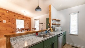 A modern kitchen with a marble countertop, green cabinets, and wooden accents.