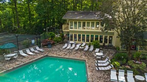 A pool area with lounge chairs and a building with large windows.