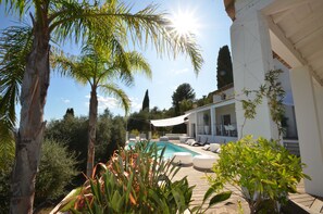 A pool area with lounge chairs, a pergola, and a modern house in the background. - DREAMING PLACE FOR HOLLYDAY (Le Tignet)