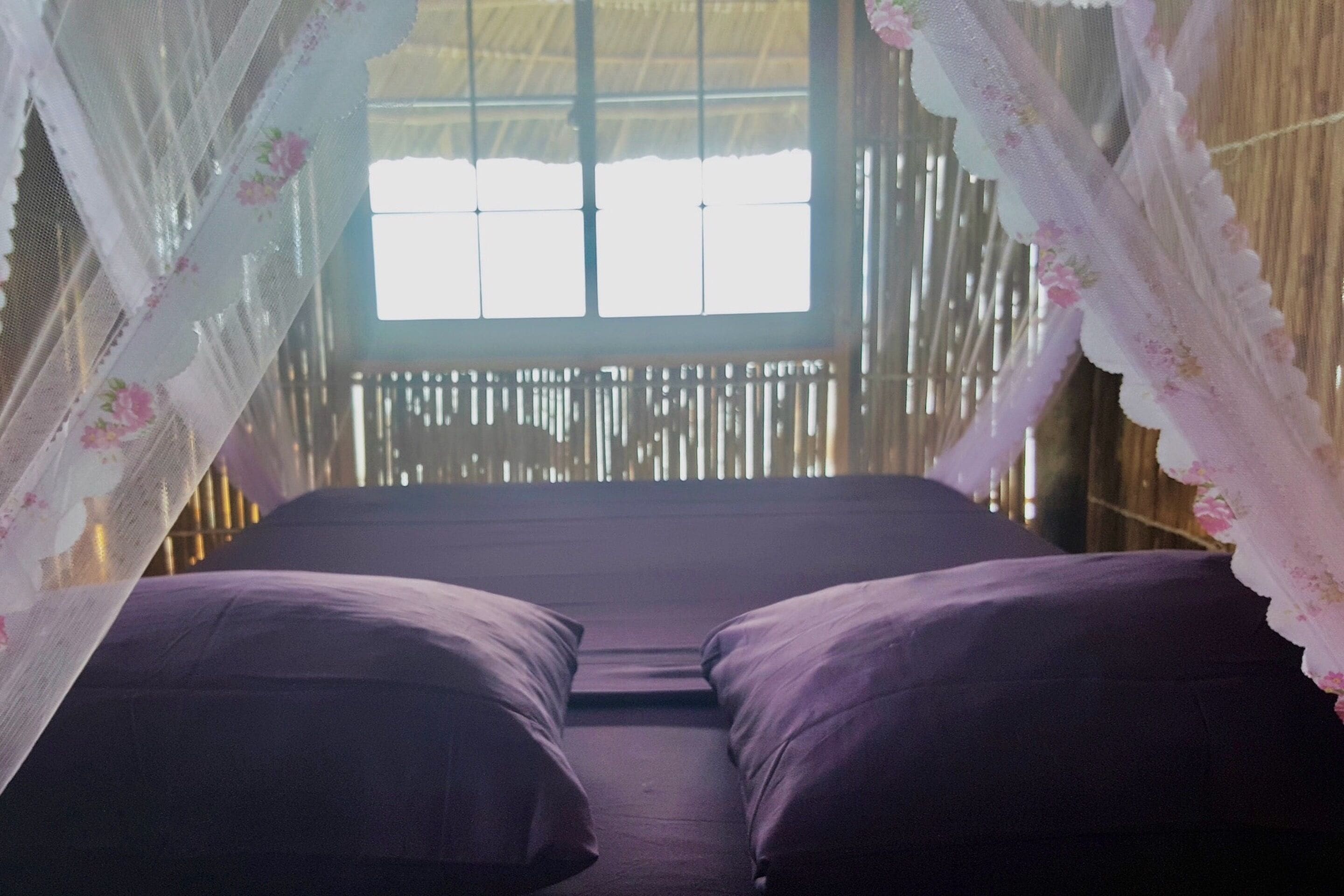 Una habitación con cama, ventana y pared de bambú.