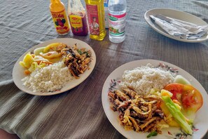 Dos platos de comida con salsas y una botella de agua sobre una mesa.