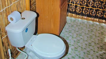 Une salle de bain avec des toilettes, un rouleau de papier toilette et un carrelage décoré.