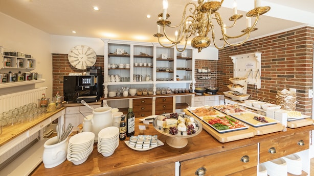 A buffet setup with various food items, a clock on the wall, and a coffee machine.