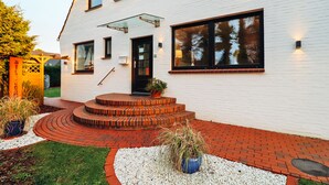A modern house with a white exterior, a glass door, and a brick staircase leading to the entrance.