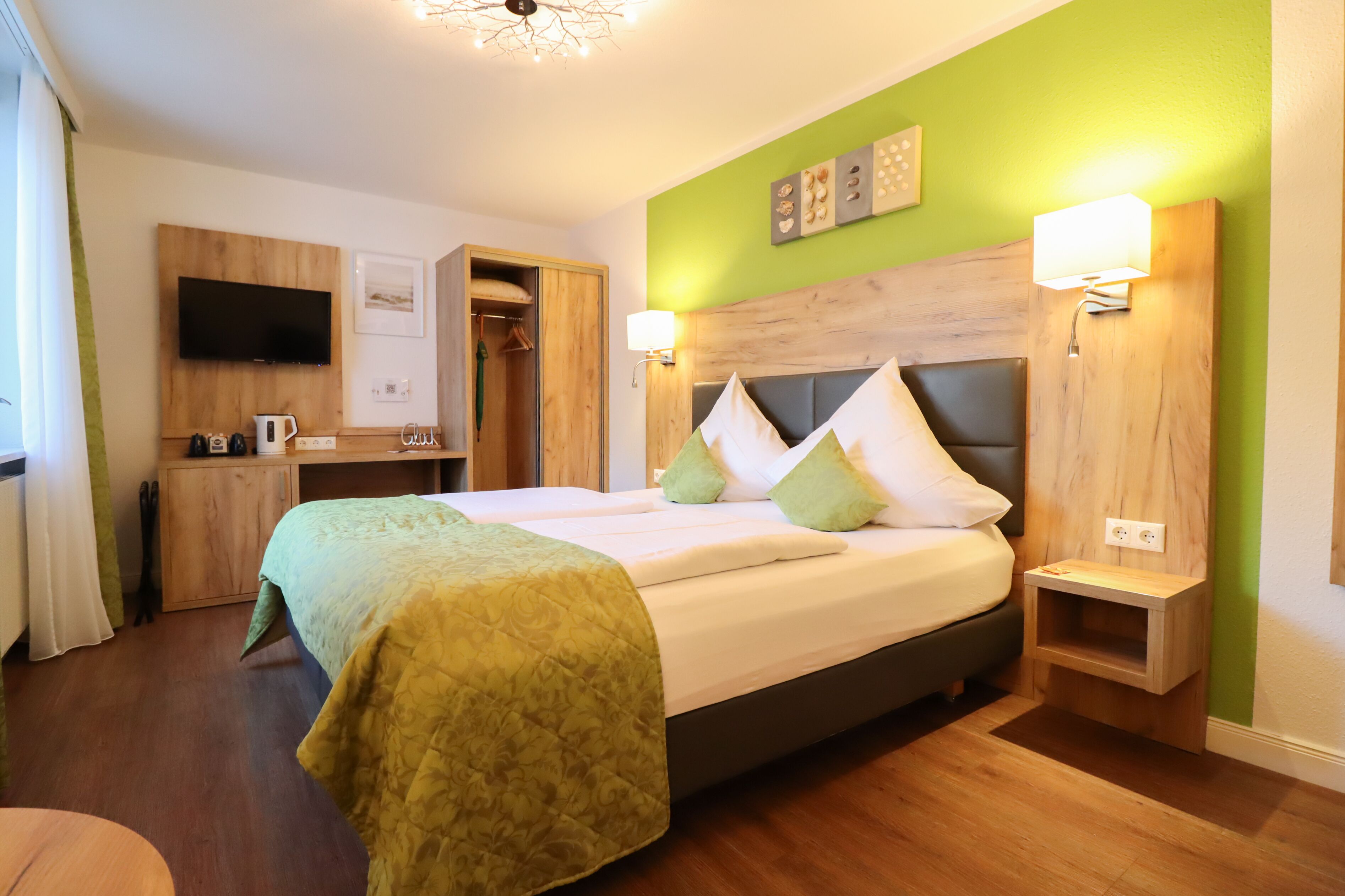 A neatly arranged hotel room with a bed, bedside table, and a small desk with a chair.