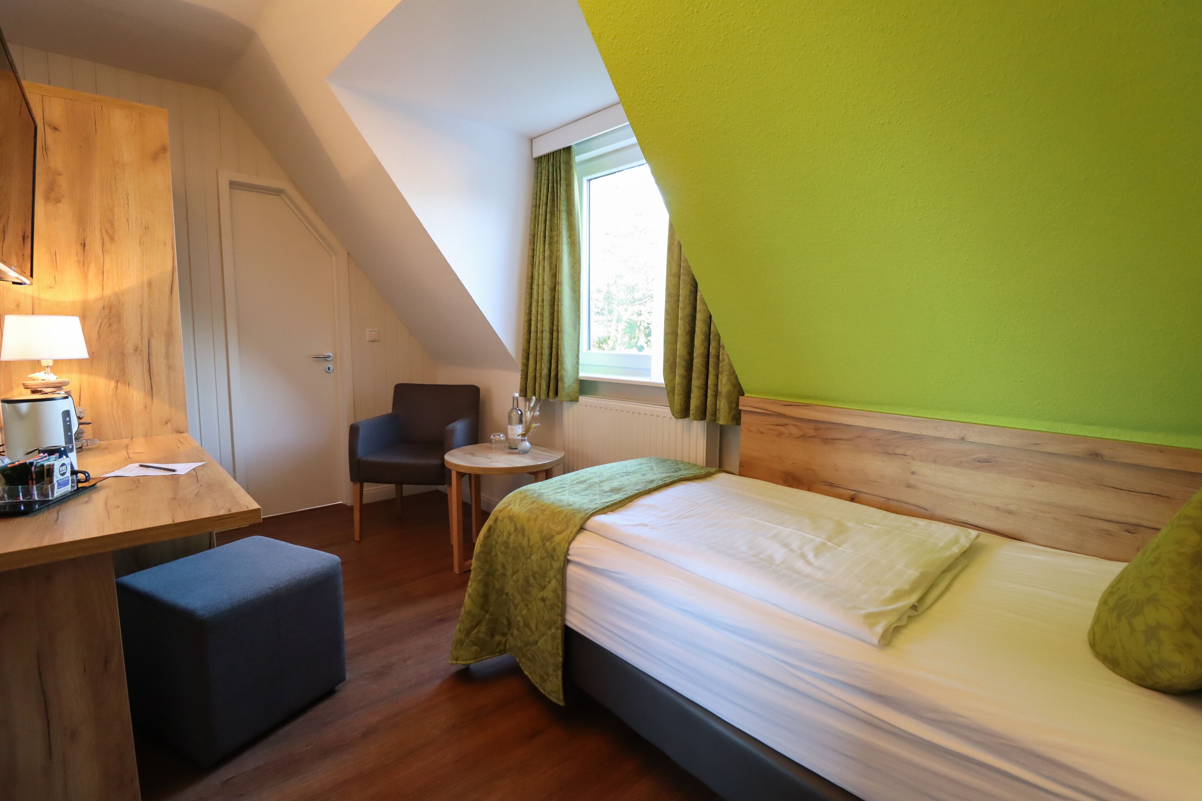 Ein Zimmer mit einem Bett, einem Schreibtisch, einem Stuhl und einem fenster mit Vorhängen.