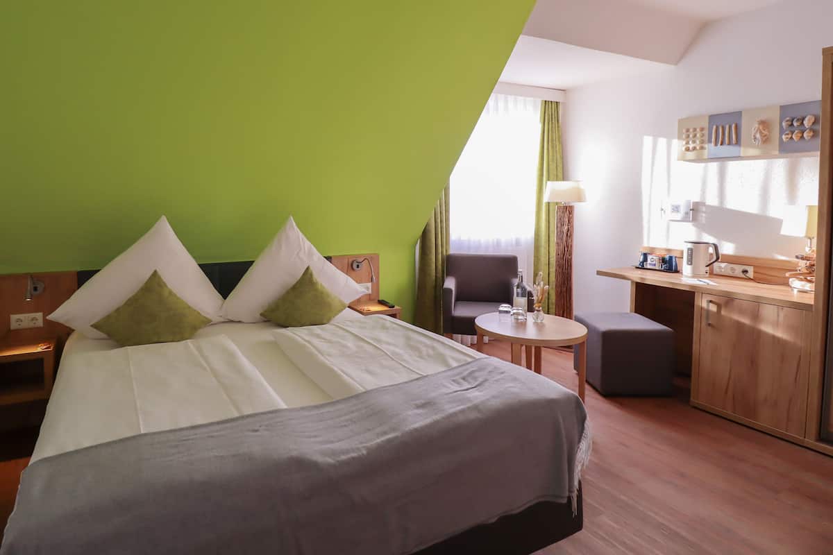 Une chambre d’hôtel avec un grand lit, un petit bureau, une chaise et une kitchenette.