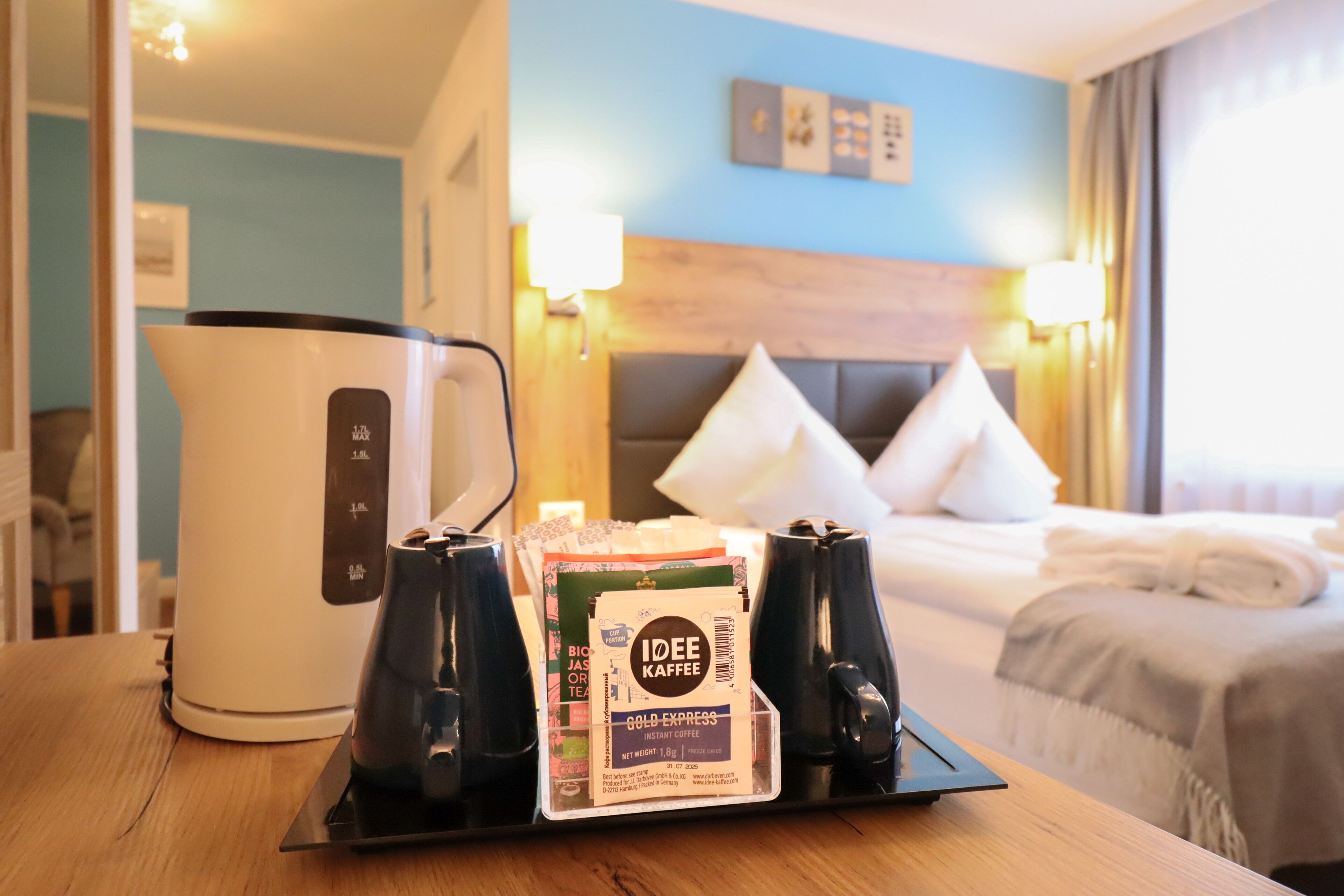 A hotel room with a bed, bedside lamps, a coffee maker, and a tray with coffee pods and a tea bag.