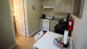 A compact kitchen with a stove, sink, and a white table with a placemat. - Stylish comfortable suite (San Antonio)