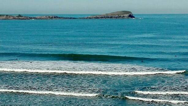 Une vue sur la côte, avec des vagues et une étendue de terre visible au loin.