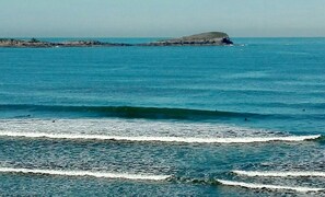 Vista costera con olas y una masa de tierra en la distancia.
