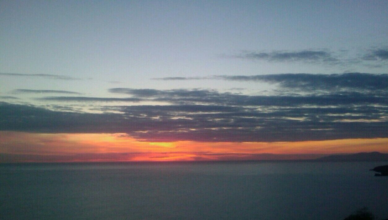 A sunset over a body of water with a clear horizon.