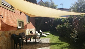 A patio with a table and chairs, a brick wall, and a yellow shade sail.
