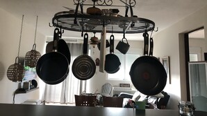 Una cocina con un colgador para ollas que contiene diferentes utensilios de cocina.