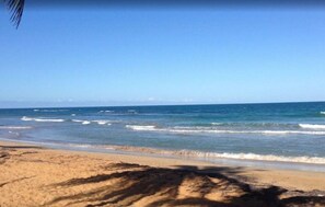 Una playa con cielos despejados y olas tranquilas.