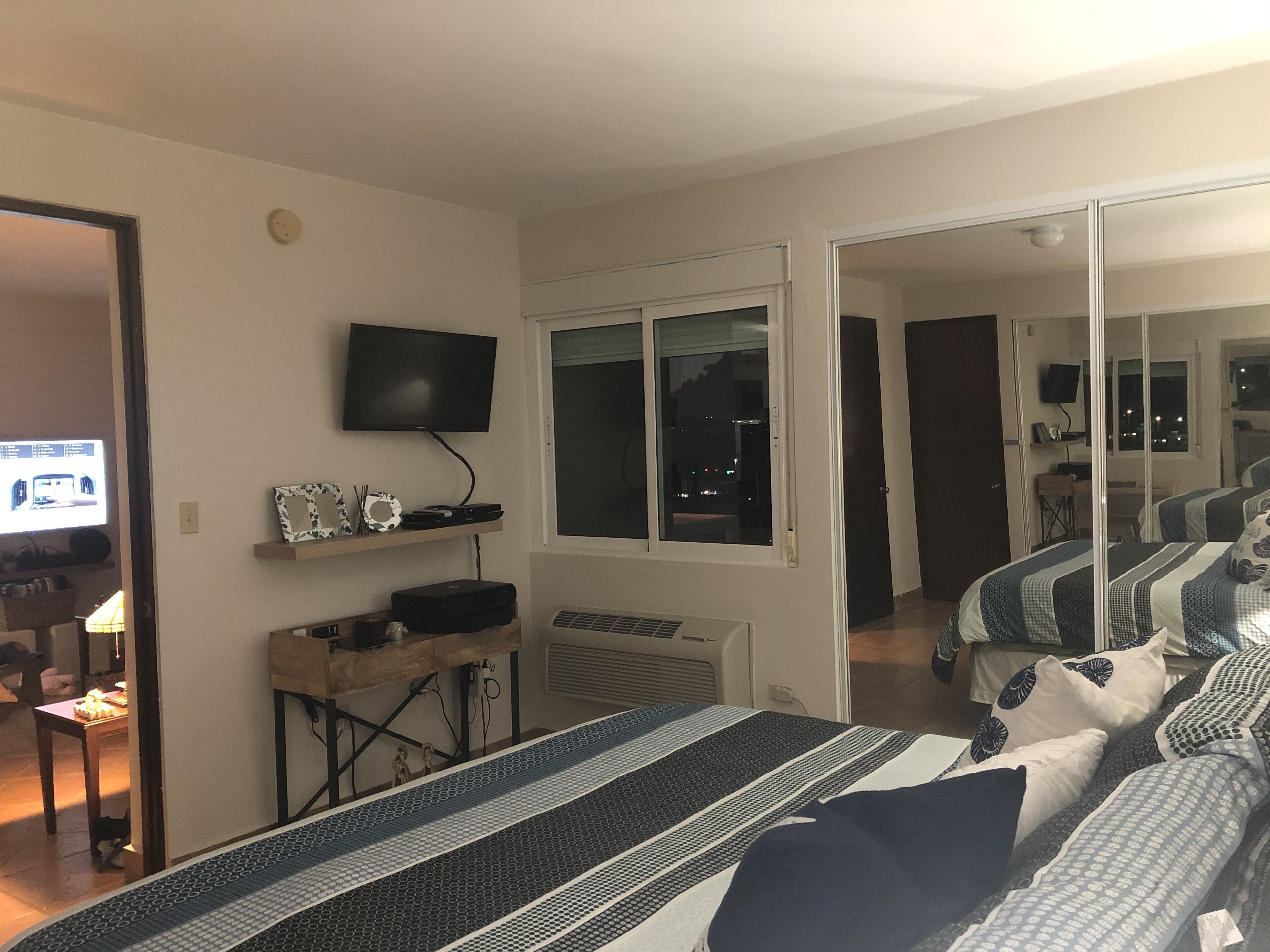 Een slaapkamer met een bed, televisie, bureau en raam.