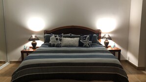 Una cama bien hecha con una colcha a rayas, dos lámparas de noche y cojines decorativos.