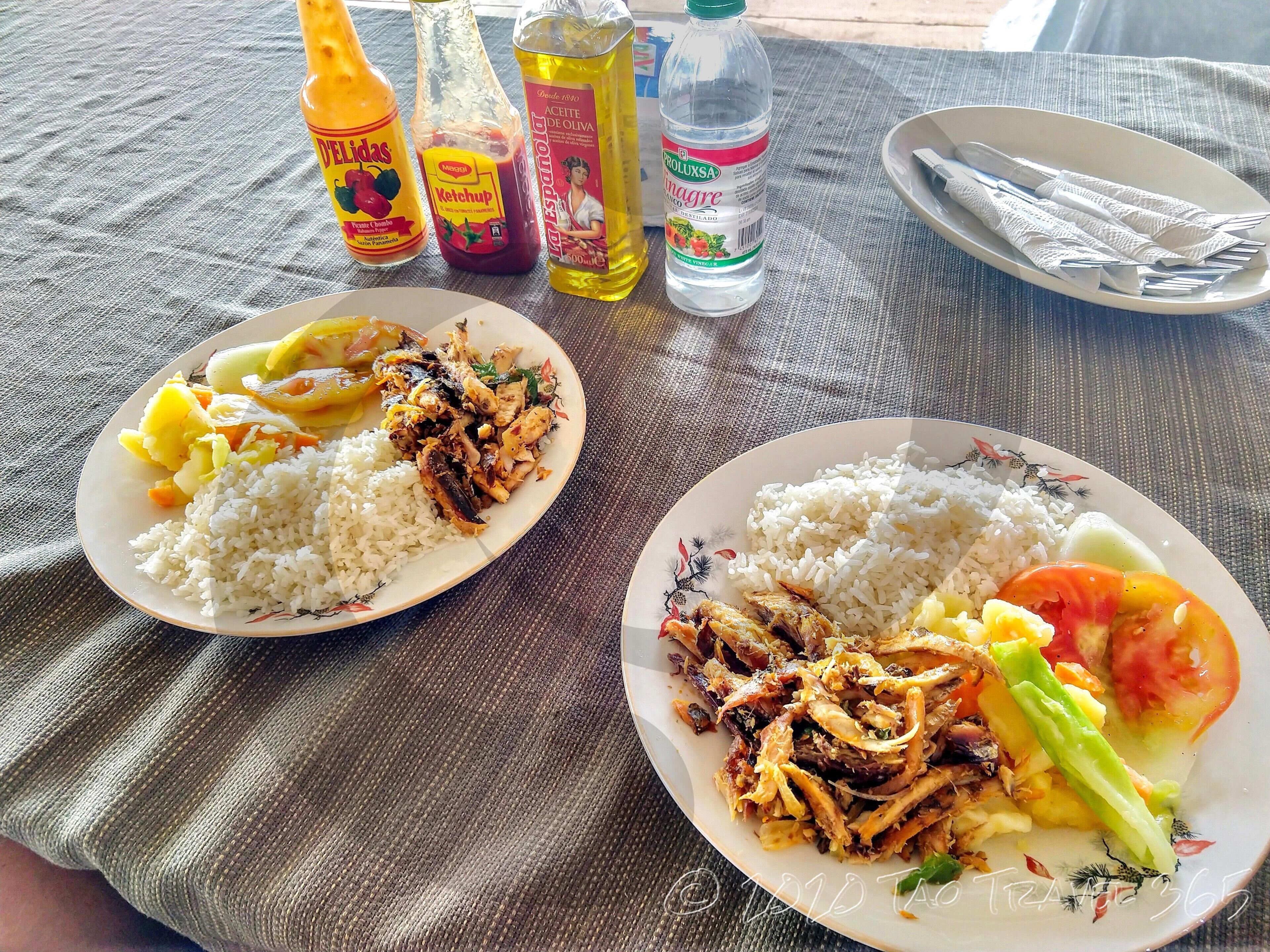 Two plates of food with condiments and a bottle of water on a table.