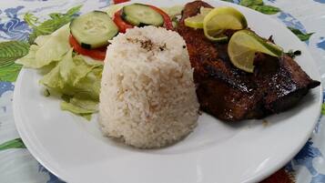 Un plato con carne a la parrilla, arroz y una ensalada.